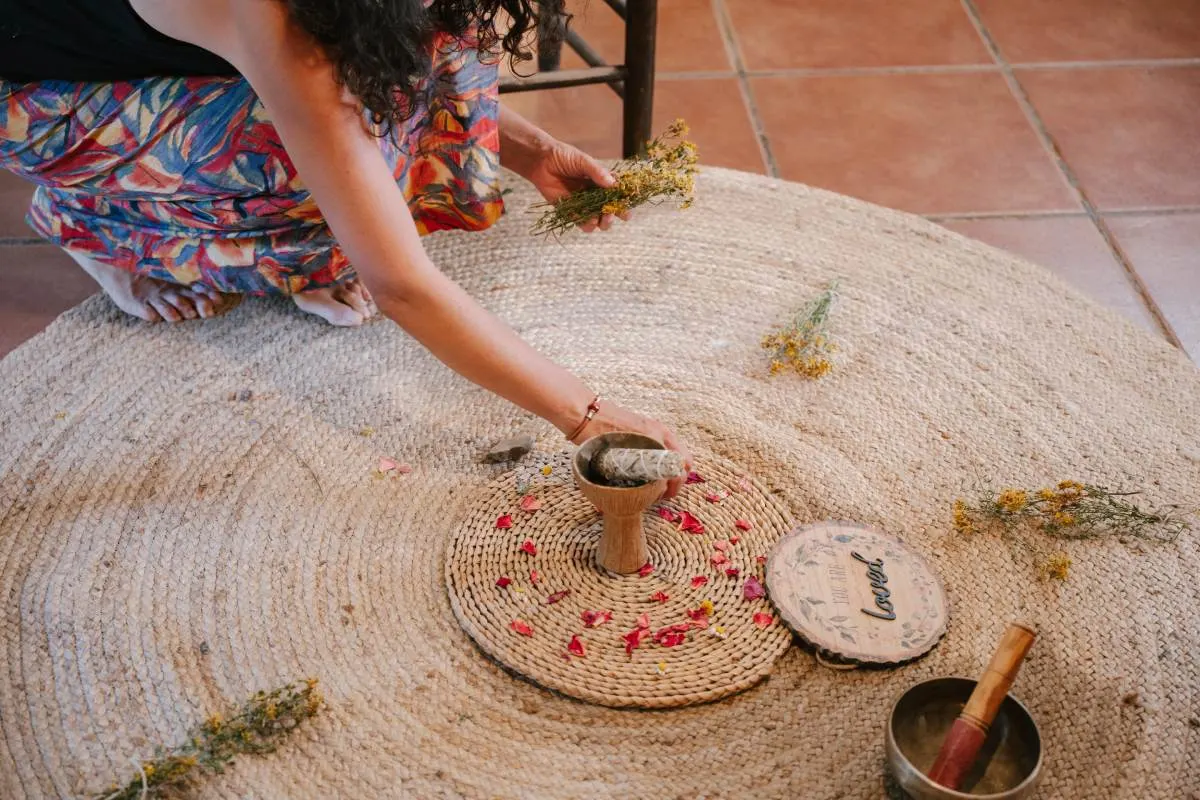 Preparación de un ritual con hierbas, pétalos y un cuenco tibetano sobre una alfombra